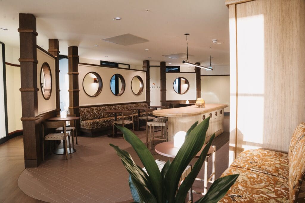 Kitchen and breakout area at The Work Project, featuring warm timber finishes, booth seating, circular wall openings and integrated Artus Air units.
