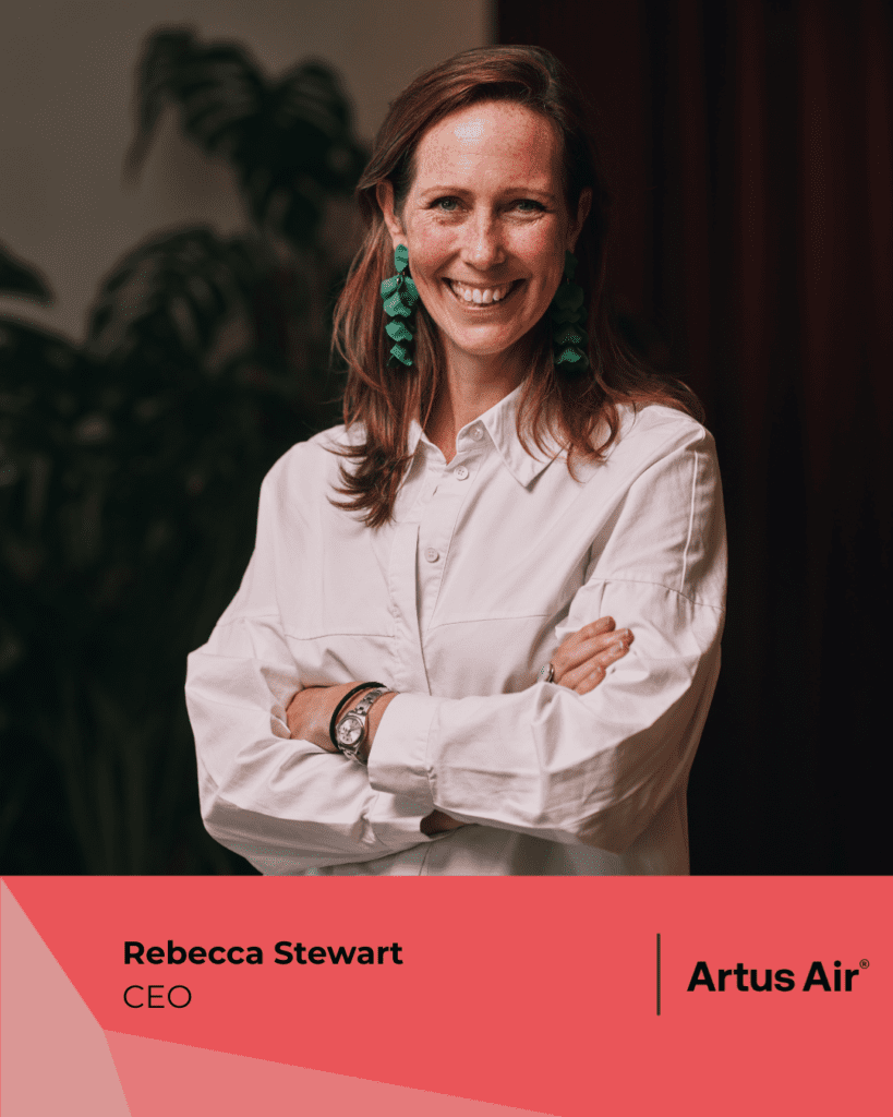 Rebecca Stewart, CEO of Artus Air, smiling with arms crossed, wearing a white shirt and green earrings.